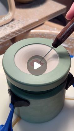 a person is using a small tool to make a bowl with some paint on it