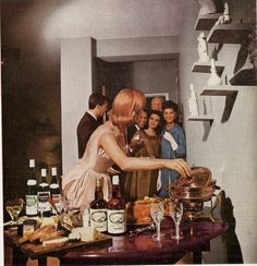 a group of people standing around a table with bottles and glasses