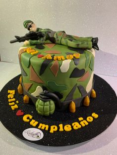 a camouflage cake with a soldier laying on it's back and the words congratulations written in spanish