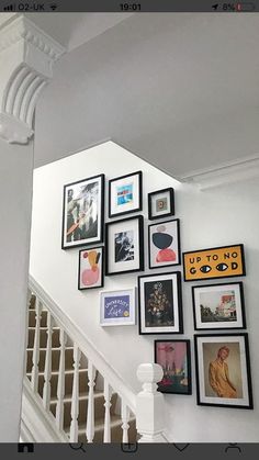 there are many framed pictures on the wall next to the bannister railings