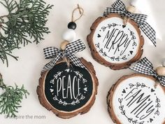 three wood slice ornaments decorated with black and white ribbon hang from twine on top of each other