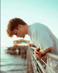 a man leaning on a railing looking down at the water