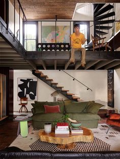 a man sitting on top of a couch in a living room next to a staircase