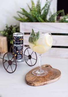 a drink sitting on top of a wooden coaster next to a can of lemonade