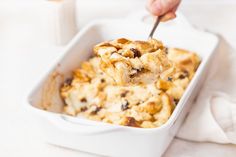 a person is spooning food out of a casserole dish with raisins