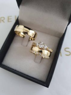 two gold wedding rings in a box with the lid open and one diamond set on top