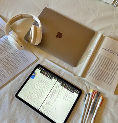 an ipad, headphones, and books on a bed