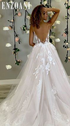 a woman in a white wedding dress standing next to a floral wall with roses on it