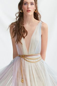 a woman in a white dress with a gold chain belt around her waist and long hair