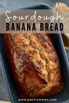 a loaf of sourdough banana bread in a blue baking pan with the words sourdough banana bread