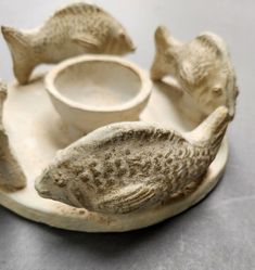 three ceramic fish on a plate with a bowl