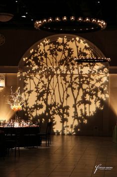 shadows cast on the wall and tables in front of them at a restaurant with chandeliers hanging from the ceiling