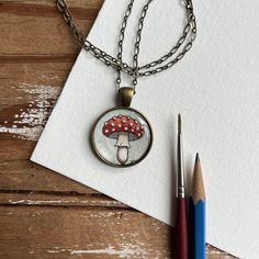 a piece of paper with a mushroom on it next to two pencils and a pen