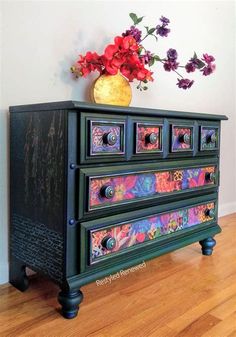 a painted dresser with flowers in a vase on top