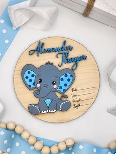 a wooden plaque with an elephant on the front and blue dots around it, sitting on a table