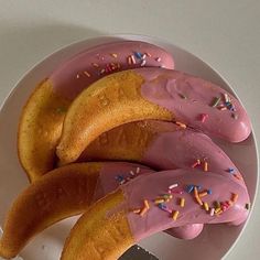 three doughnuts with pink frosting and sprinkles on a plate