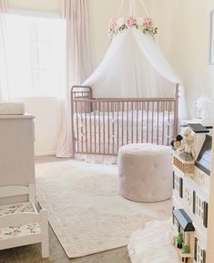 a baby's room with a white crib and pink flowers on the ceiling