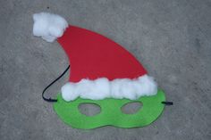 a green mask with a red santa hat on it's head is sitting on the ground