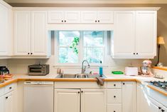 a kitchen with white cabinets and an open window