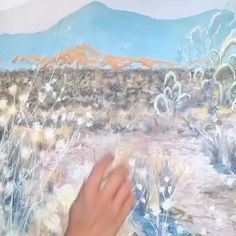 a person is painting a desert scene with brush