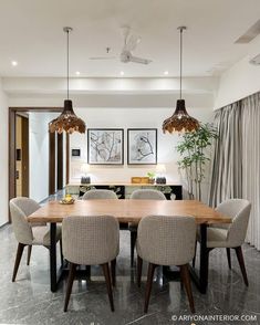 a dining room table with chairs and lights hanging from the ceiling