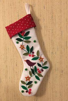 an embroidered christmas stocking hanging on a wooden wall with red polka dot trimming