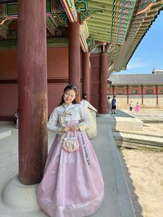 a woman in a pink dress standing next to pillars