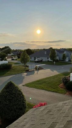 the sun is setting over some houses and lawns