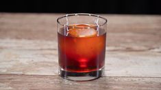 a glass filled with liquid sitting on top of a wooden table