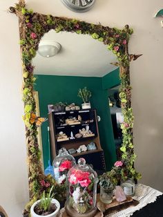 a mirror that has some plants in it and a clock on the wall behind it