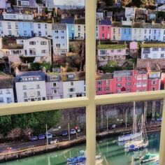 boats are docked in the water near some houses and buildings, as seen through a window