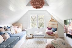 a living room filled with furniture and a hanging chair next to a window on top of a white wall