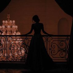 a woman is standing on a balcony looking out at the chandelier in the background