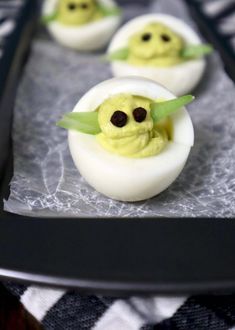 deviled eggs with yogurt and chocolate eyes are on a black serving tray