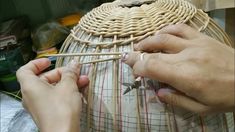 two hands are working on an object made out of bamboo