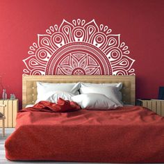 a bedroom with red walls and an intricately designed wall decal above the bed