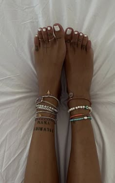 a woman's feet with tattoos and bracelets on them