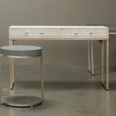 a white desk with two drawers and a stool next to it on a concrete floor