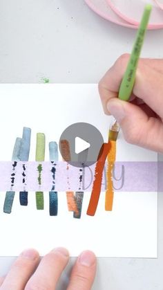 someone is holding a pencil and drawing with colored crayons