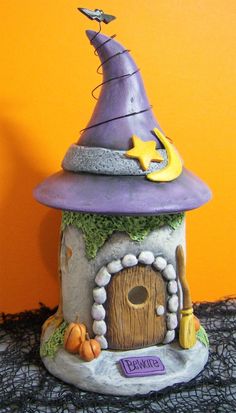 a purple witch's hat is on top of a small house with a door