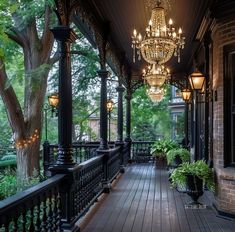 a porch with lights and potted plants on the railings, surrounded by trees