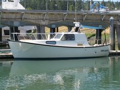 a white boat is docked under a bridge