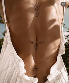 the back of a woman's white dress with tattoos on her lower and lower back