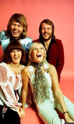 the bee gees are posing for a photo in front of a pink background with their mouths open