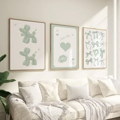 three framed pictures hang on the wall above a couch in a living room with white furniture