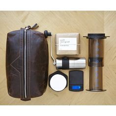 the contents of a travel bag laid out on a wooden table with coffee and other items