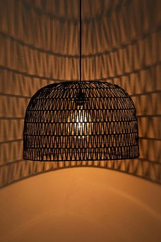 a light that is hanging from a ceiling in front of a wall with wicker covering it