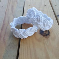 two white ropes tied together on top of a wooden table next to a small piece of wood