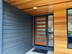 the front door of a modern home with wood paneling