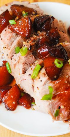 the meat is covered in sauce and green onions on the plate, ready to be eaten